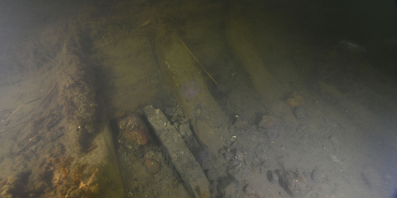 En grumlig bild av en del av ett vrak på havsbotten.