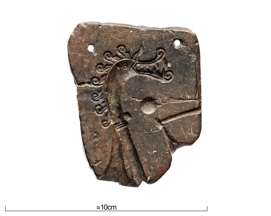 En stentavla med två hål och ett inristat drakhuvud.