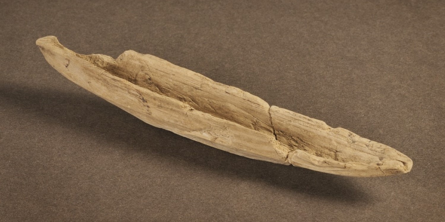 Liten urgröpt träbit formad som en enkel leksaksbåt.