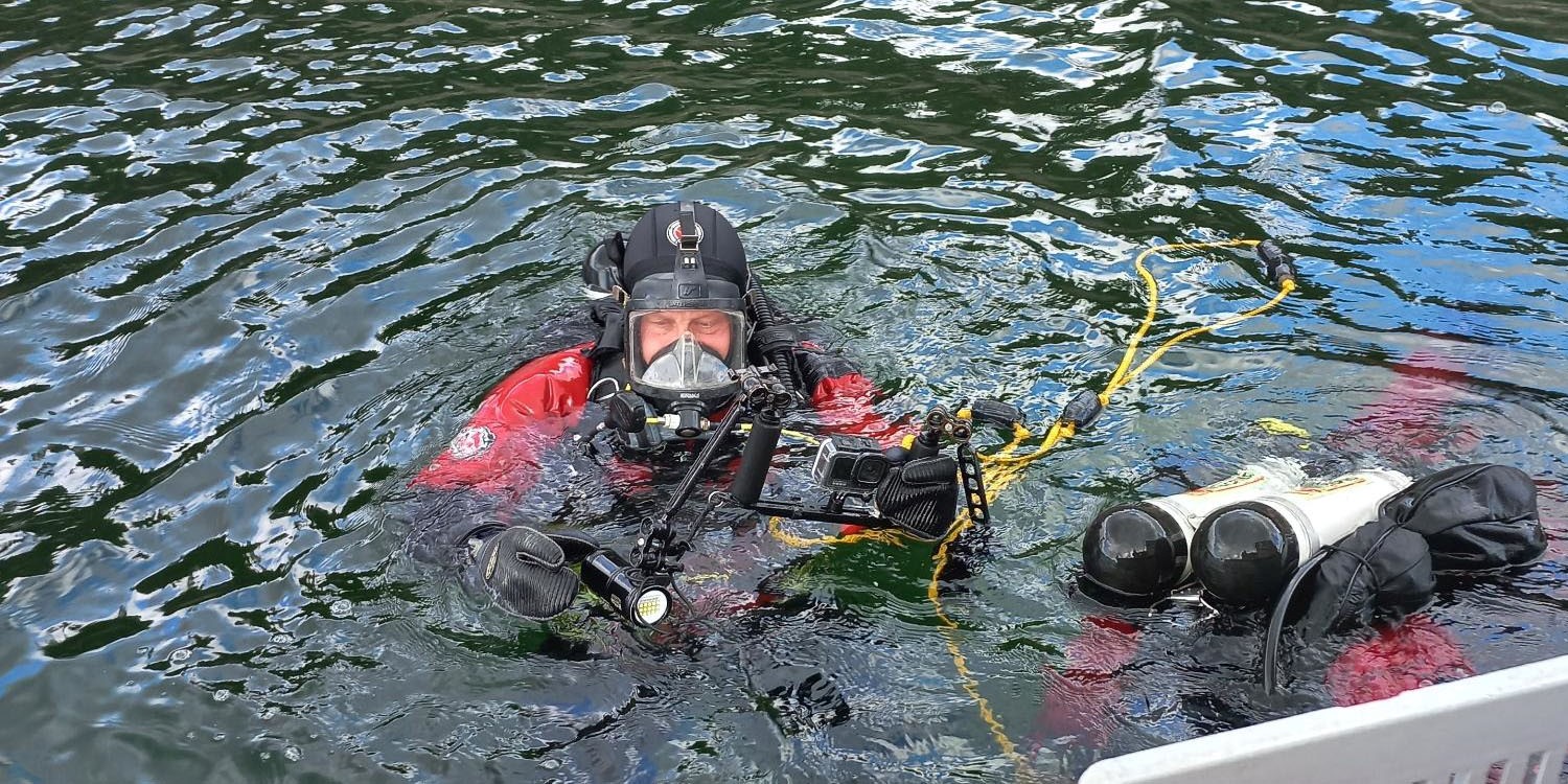 En dykare kollar sin fotoutrustning uppe vid ytan.