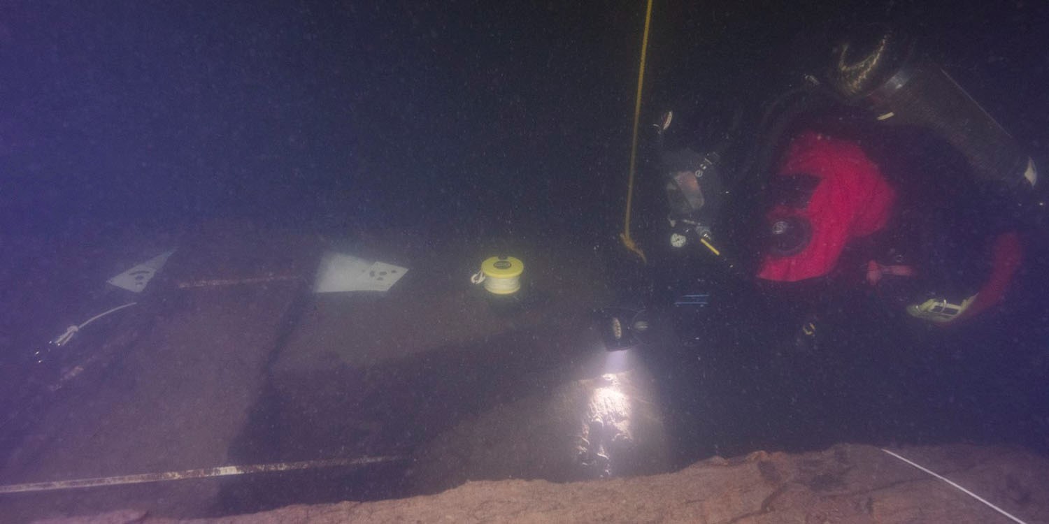 En dykare ses undersöka något nere i vattnet. 