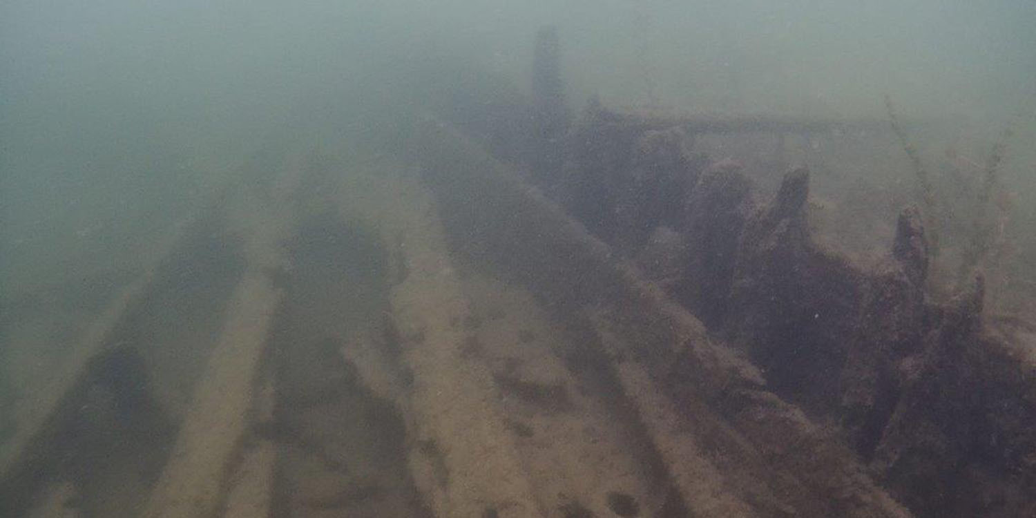 Ett vrak syns på botten, vattnet är grumligt.