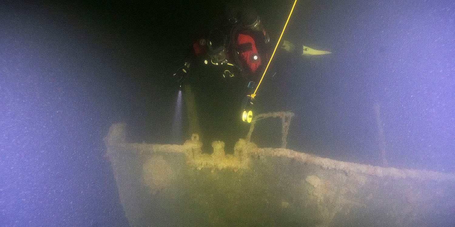 En dykare undersöker ett vrak på havets botten.