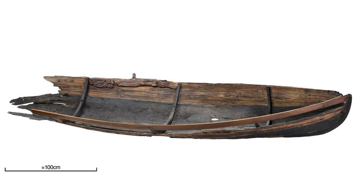 Sidovy av en skadad träbåt mot vit bakgrund.