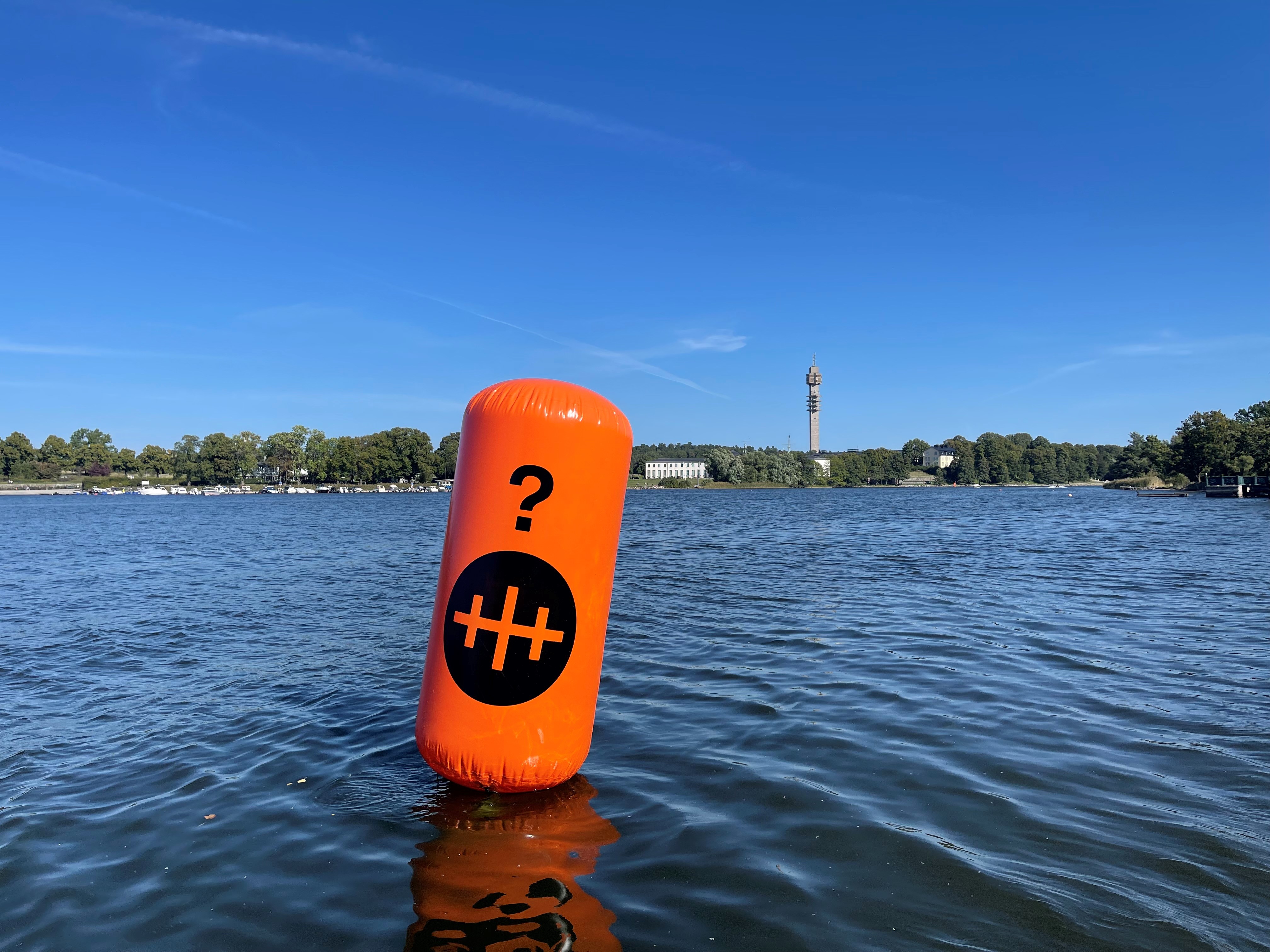 Orangefärgad boj på Stockholms vatten, Kaknästornet i bakgrunden.