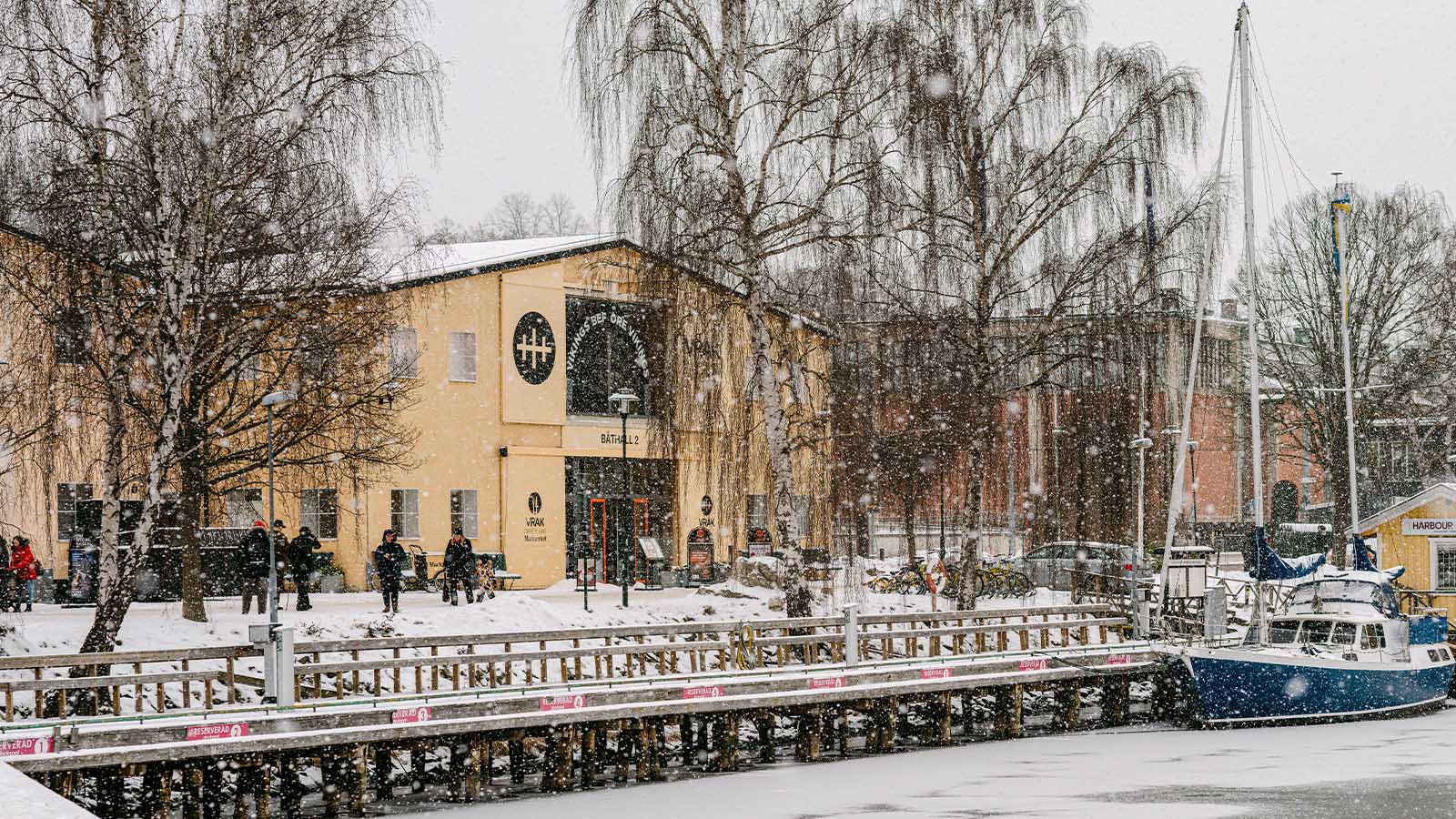 Foto av museet Vrak sett från brygga utanför museet, byggnaden är ljusgul och vädret snöigt.
