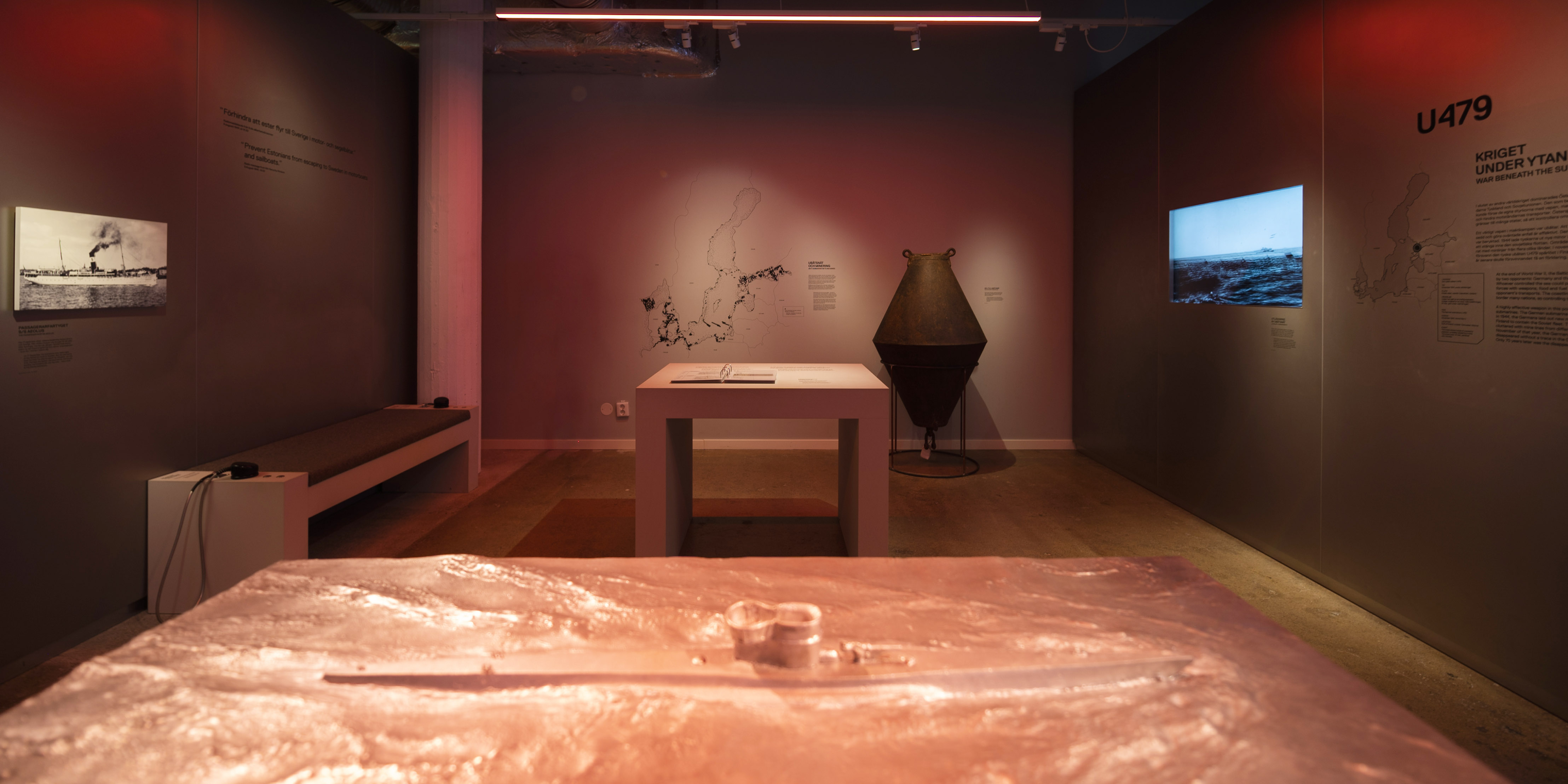 Utställningsrum om ubåten U479 med föremål, karta och filmvisning på vägg.