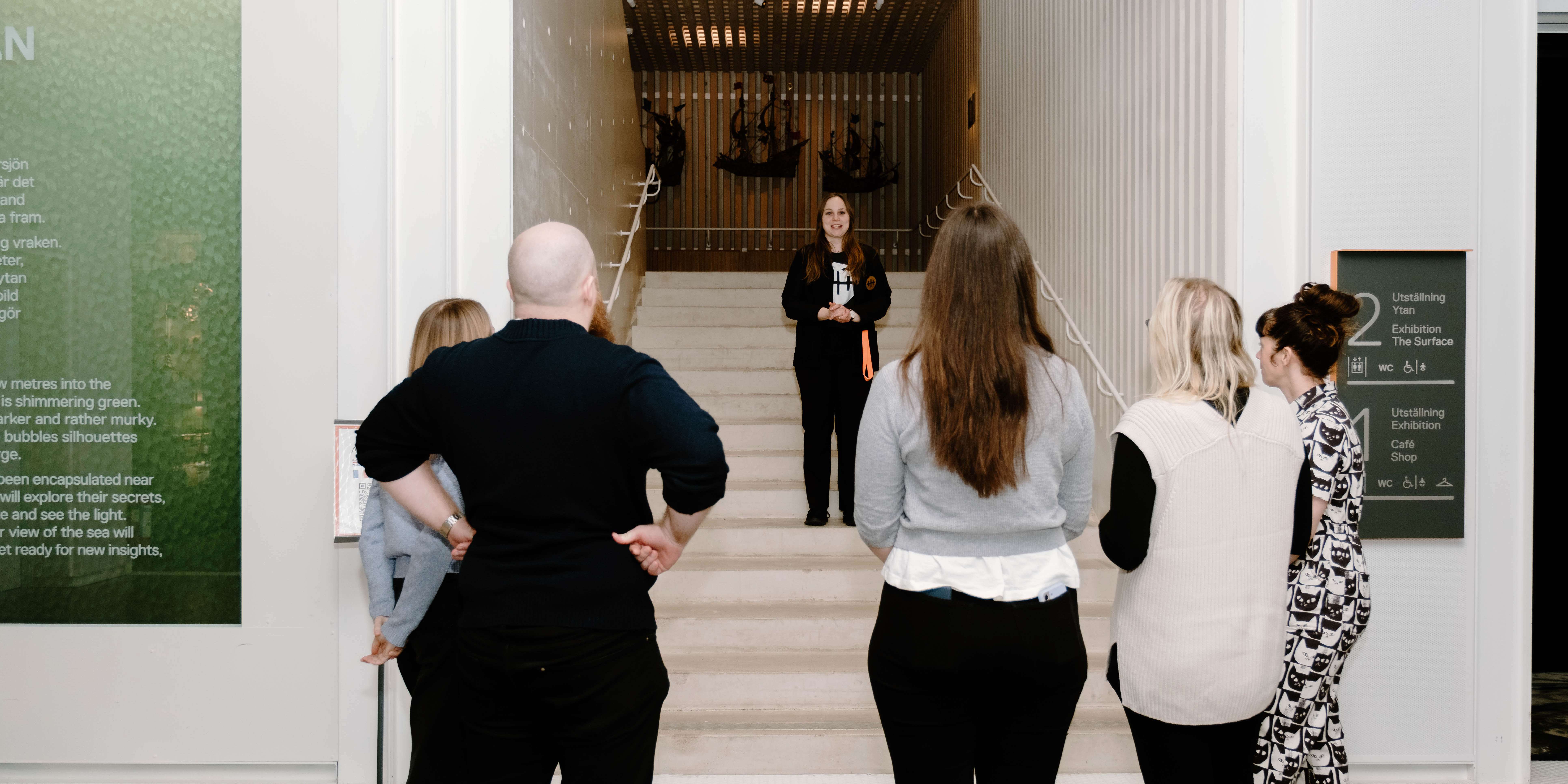 Guide står i en trappa och talar till en grupp besökare i museets entré.