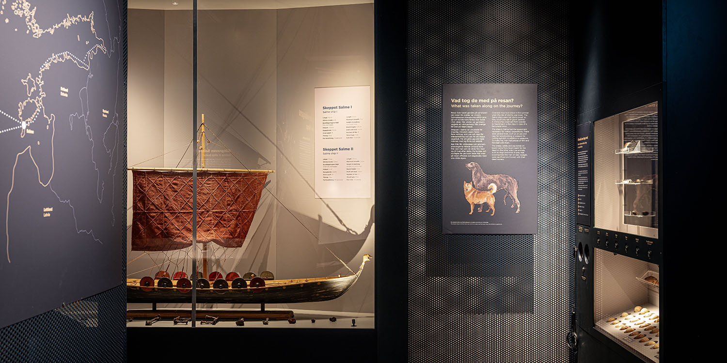 Modell av vikingaskepp funnet i Salme i glasmonter med informationsskyltar på väggarna.