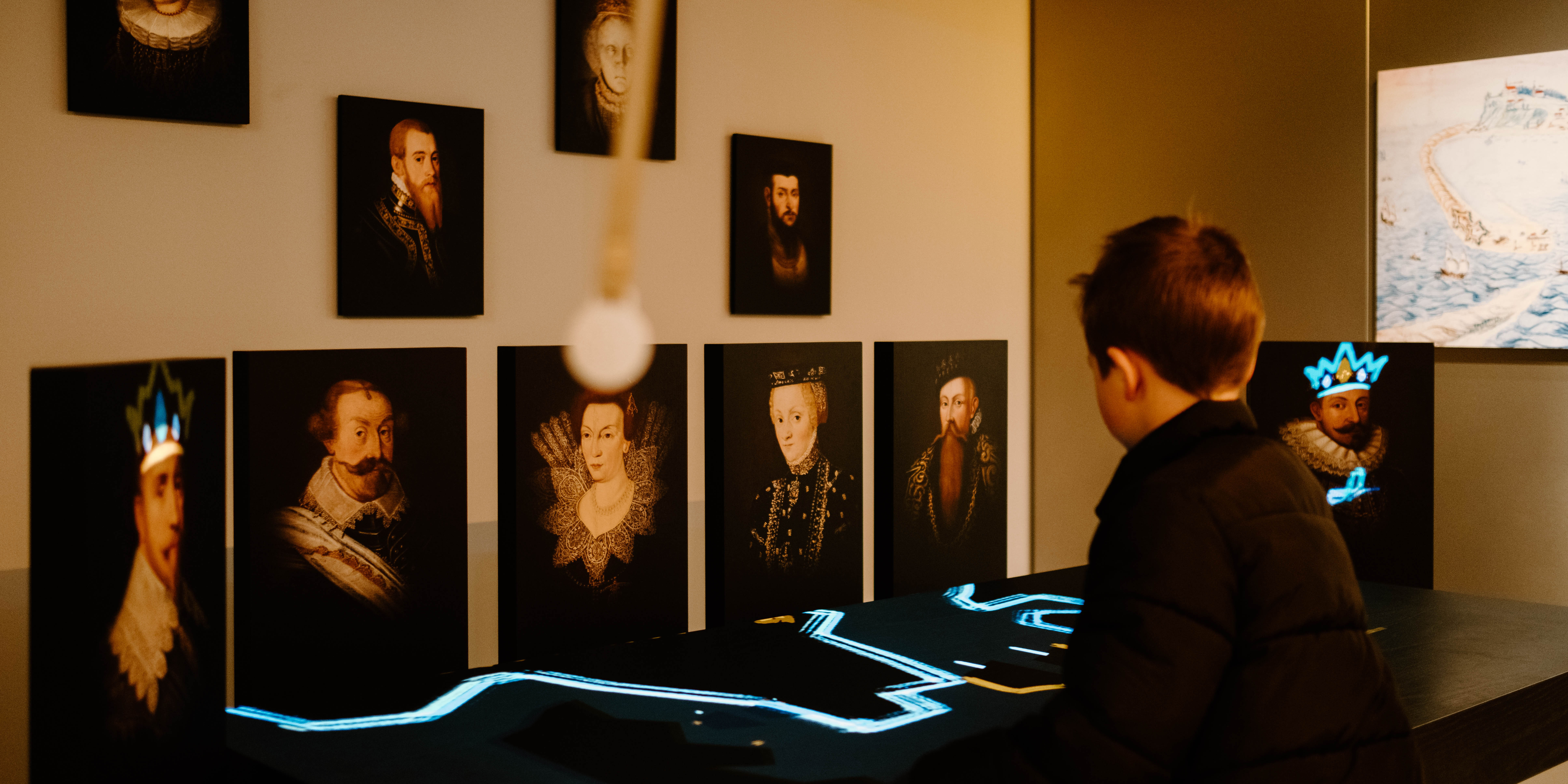 Barn använder interaktiv station framför porträttmålningar med digitala effekter.