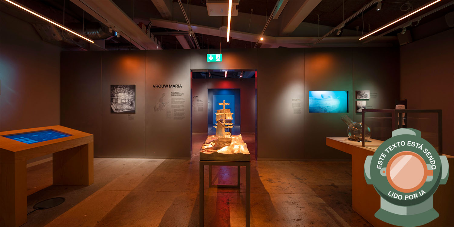 Rödtonad bild av utställning i museum med modell av segelfartyg i mitten. Bilden är märkt med en dykhjälm och texten: Este texto está sendo lido por IA