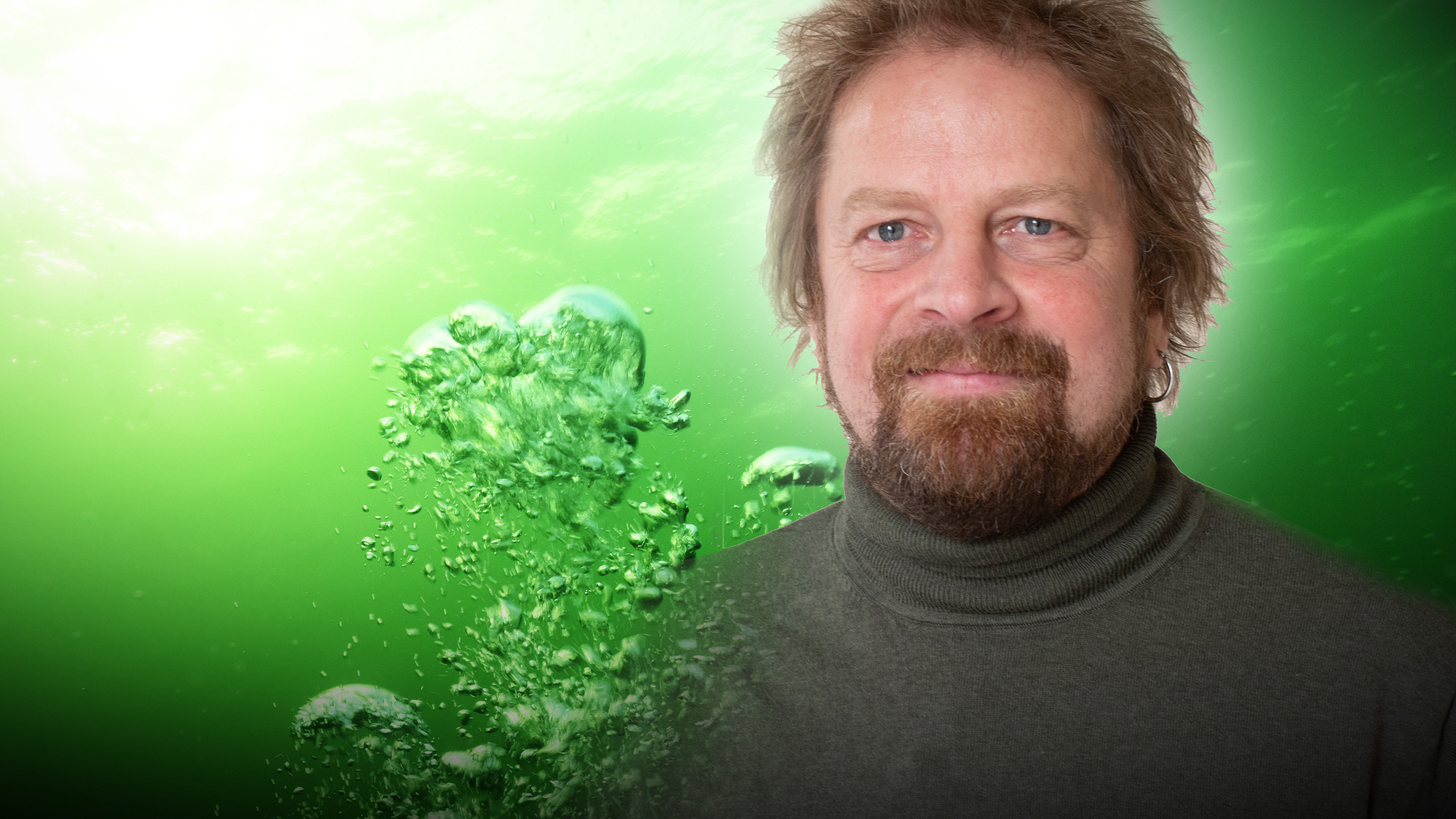 Man med brunt hår i grön tröja mot bakgrund av bubblor.