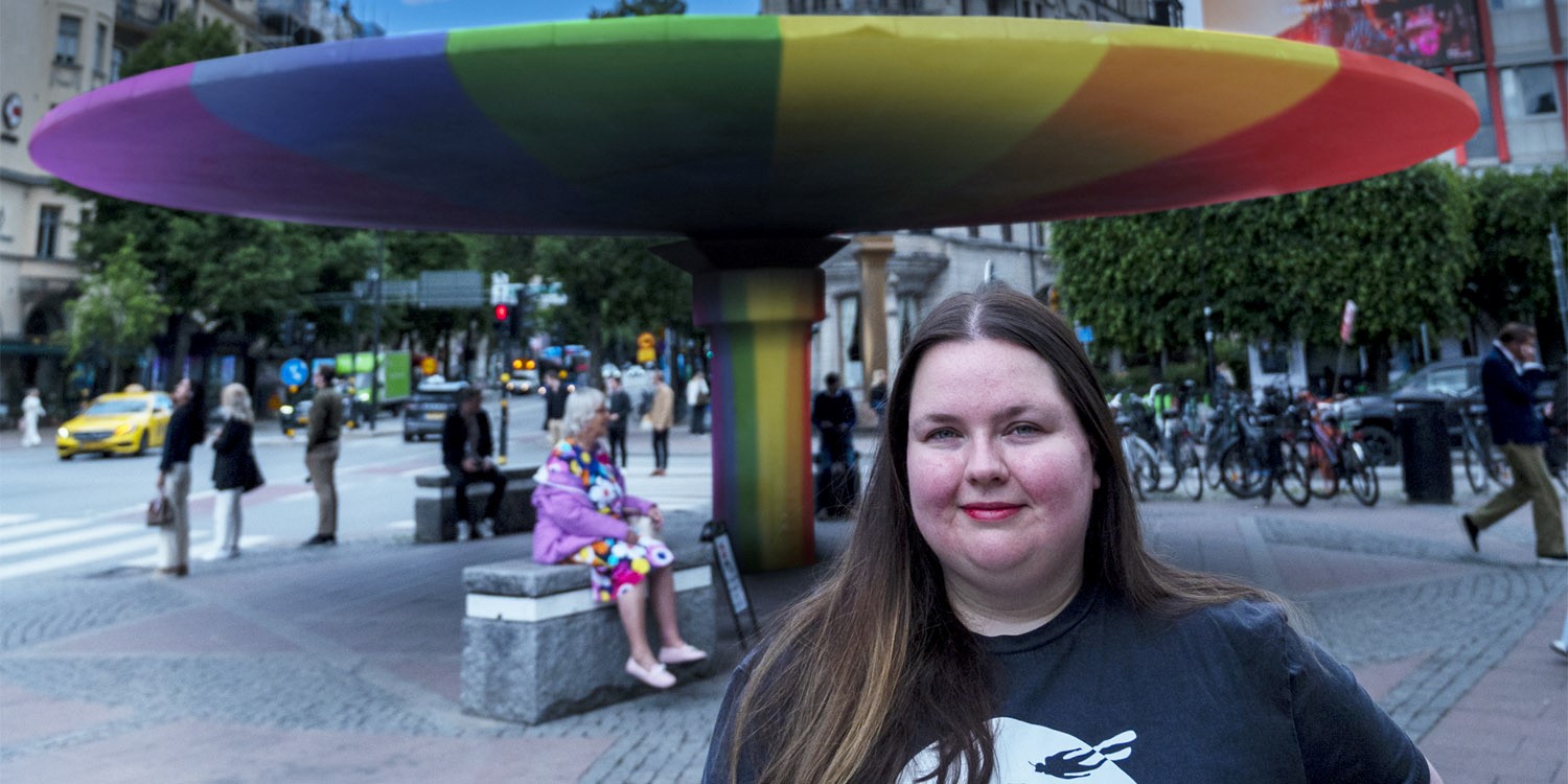 Foto på en tjej och i bakgrunden syns Stureplan i färgglada färger.