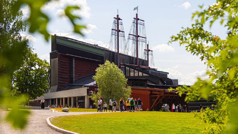 Vasamuseet, en hög byggnad med master på taket syns bredvid en gräsmatta. 