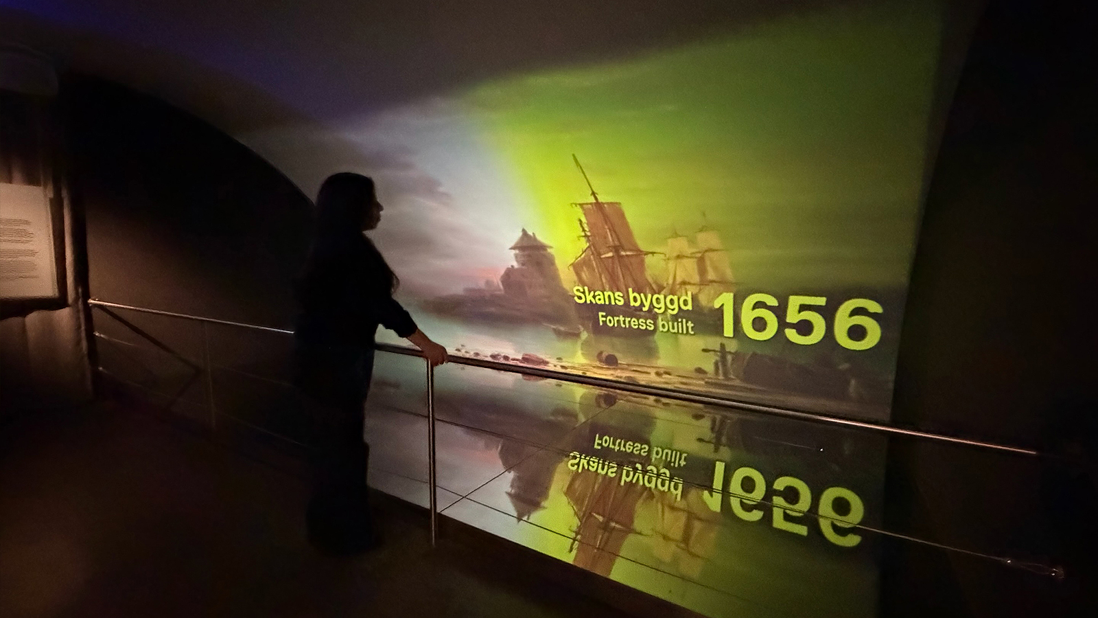 En besökare tittar på filmen som visas i utställningen Epilog