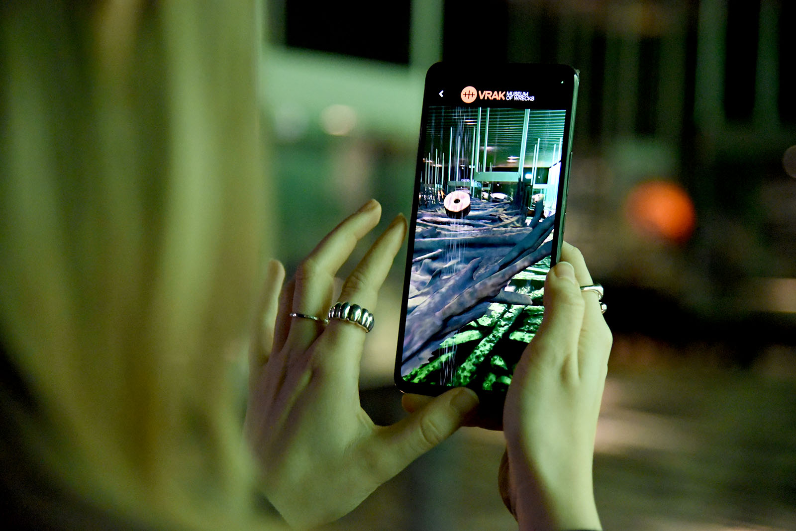 En besökare använder en smart telefon för att utforska utställningen med hjälp av en app, där vraket efter Resande Man levandegörs med hjälp av AR.