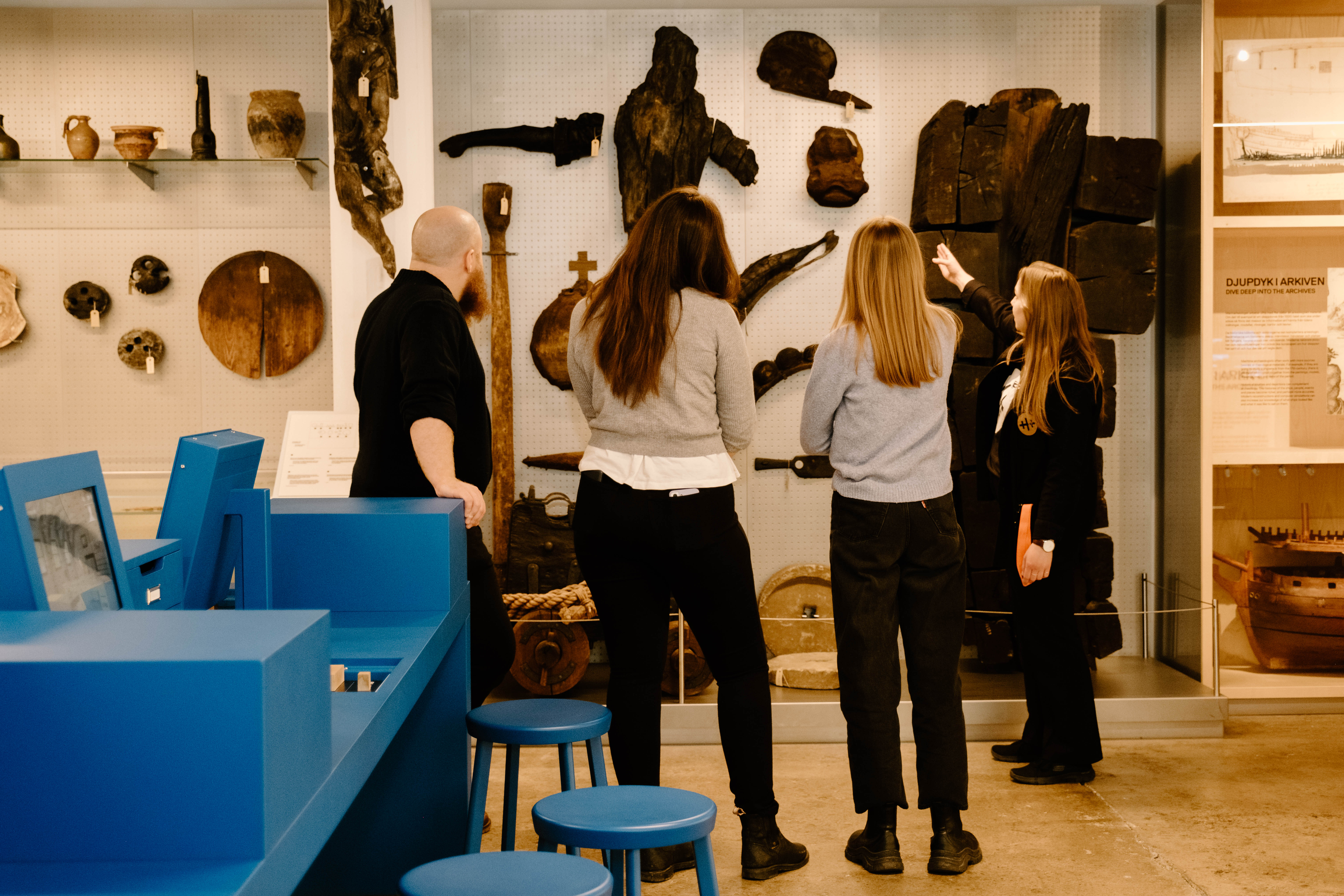 En grupp museibesökare tittar på föremål från ett skeppsvrak, guidade av en museianställd.