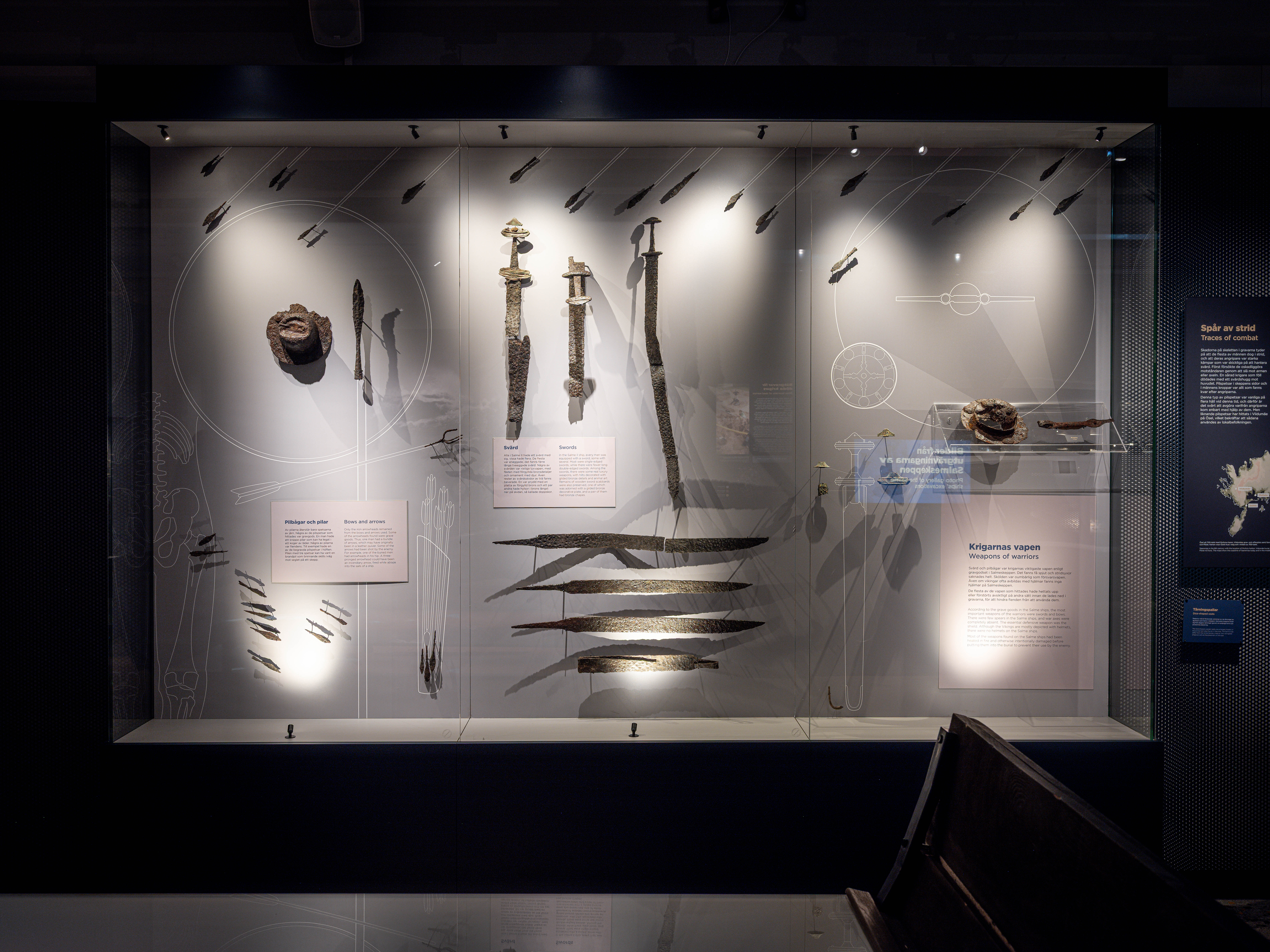 Display case featuring archaeological Viking-age finds, including swords, spearheads, and arrow points, with accompanying information panels.