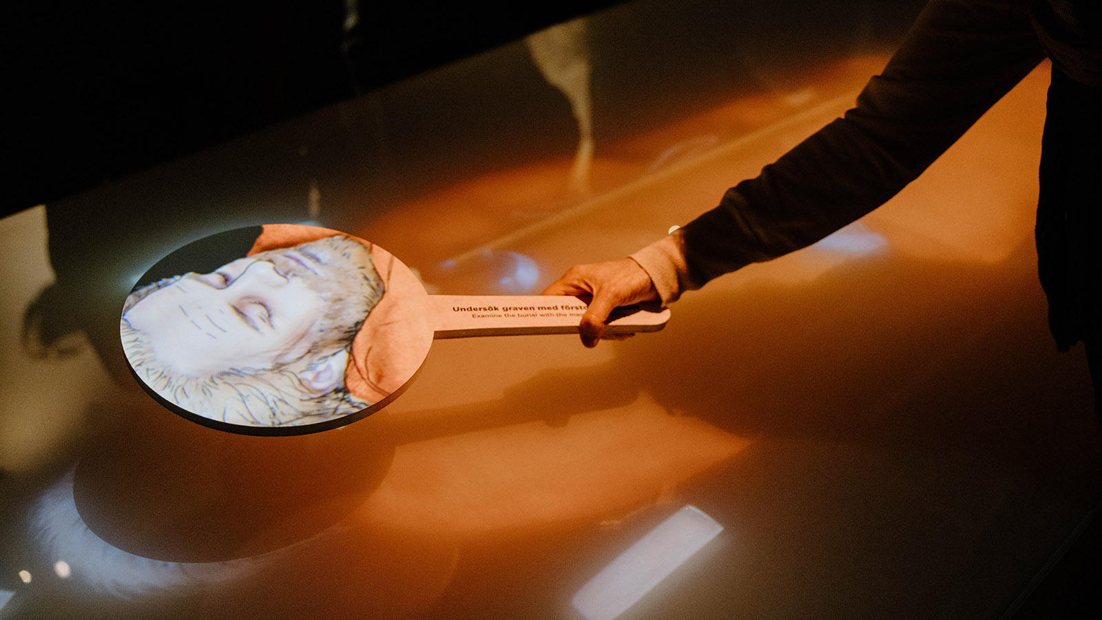 A visitor examins a grave with an interactive tool