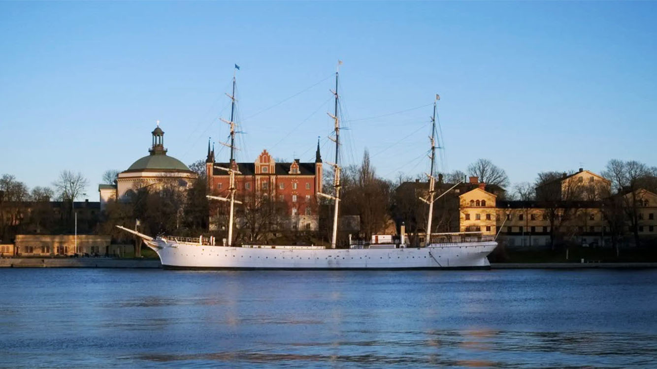 Vitt fartyg fotat från vattnet framför ön Skeppsholmen.