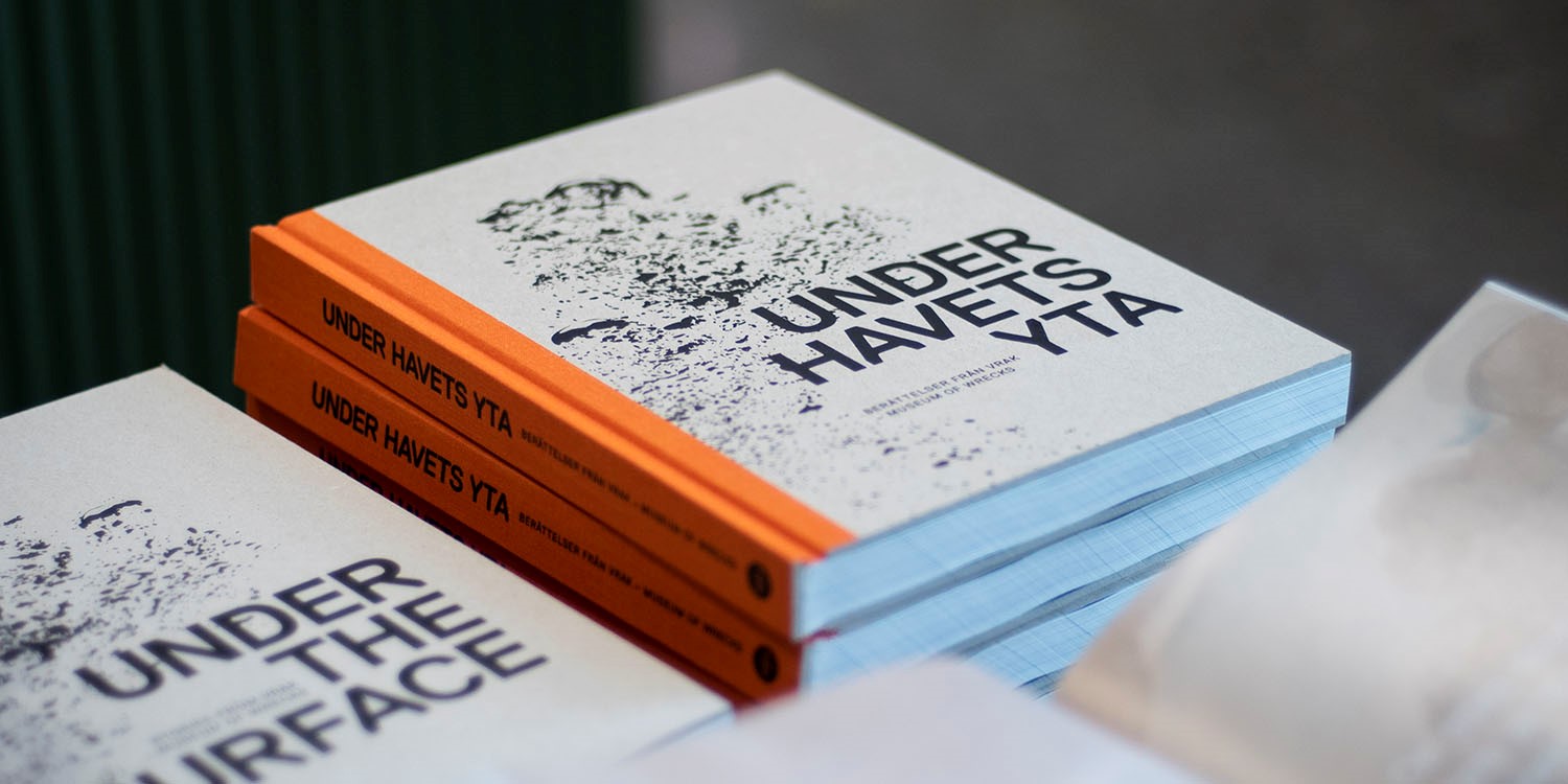 Böcker på hög med orange rygg och titeln "Under havets yta". 