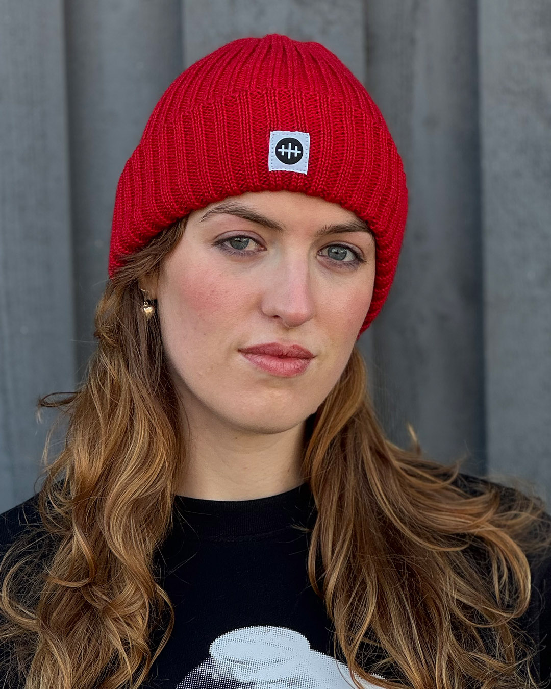 A girl wearing a red wool beanie with Vrak's logotype