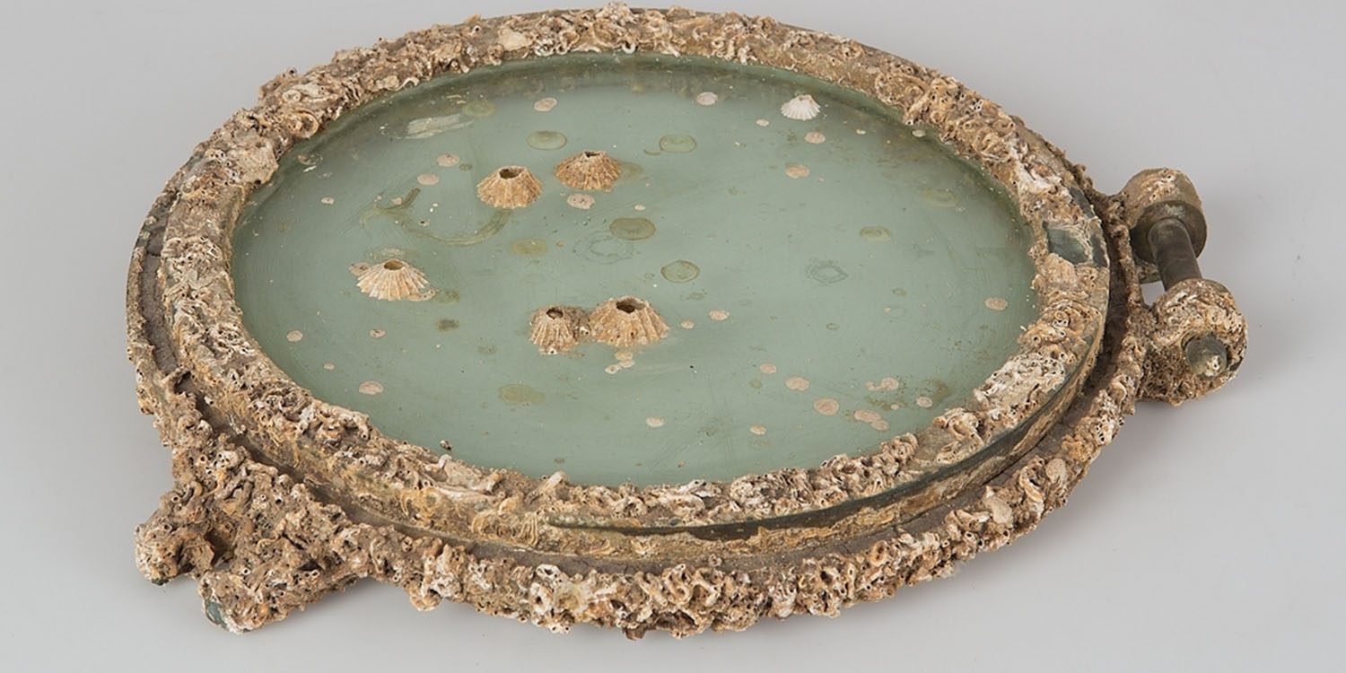 Öppningsbar ventil av mässing med glas. Kraftig påväxt av kvarsittande havstulpaner och rörmaskar.