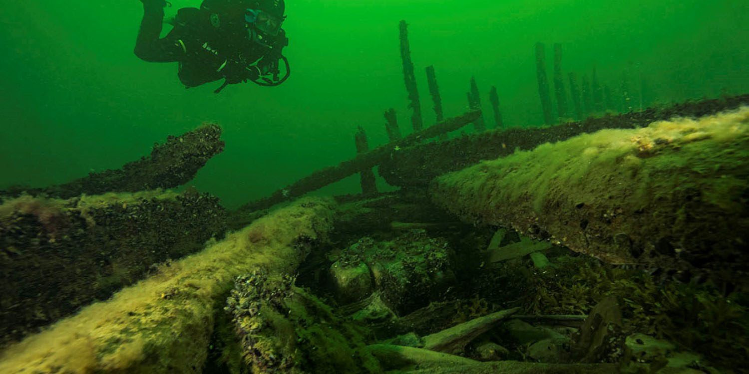 Gröntonat foto av dykare ovanför vraket av skeppet Resande man