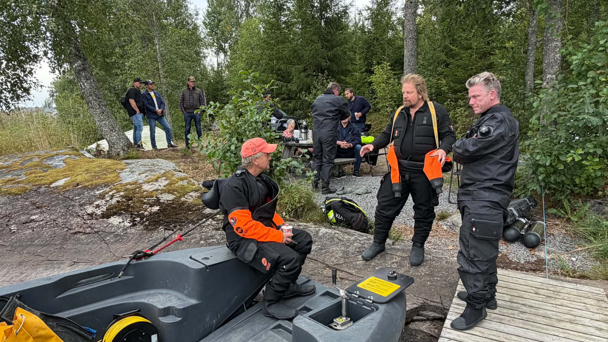 Människor på klippa vid en båt, närmast kameran står tre personer i dykarutrustning, en av dem är Pål Jonsson. 