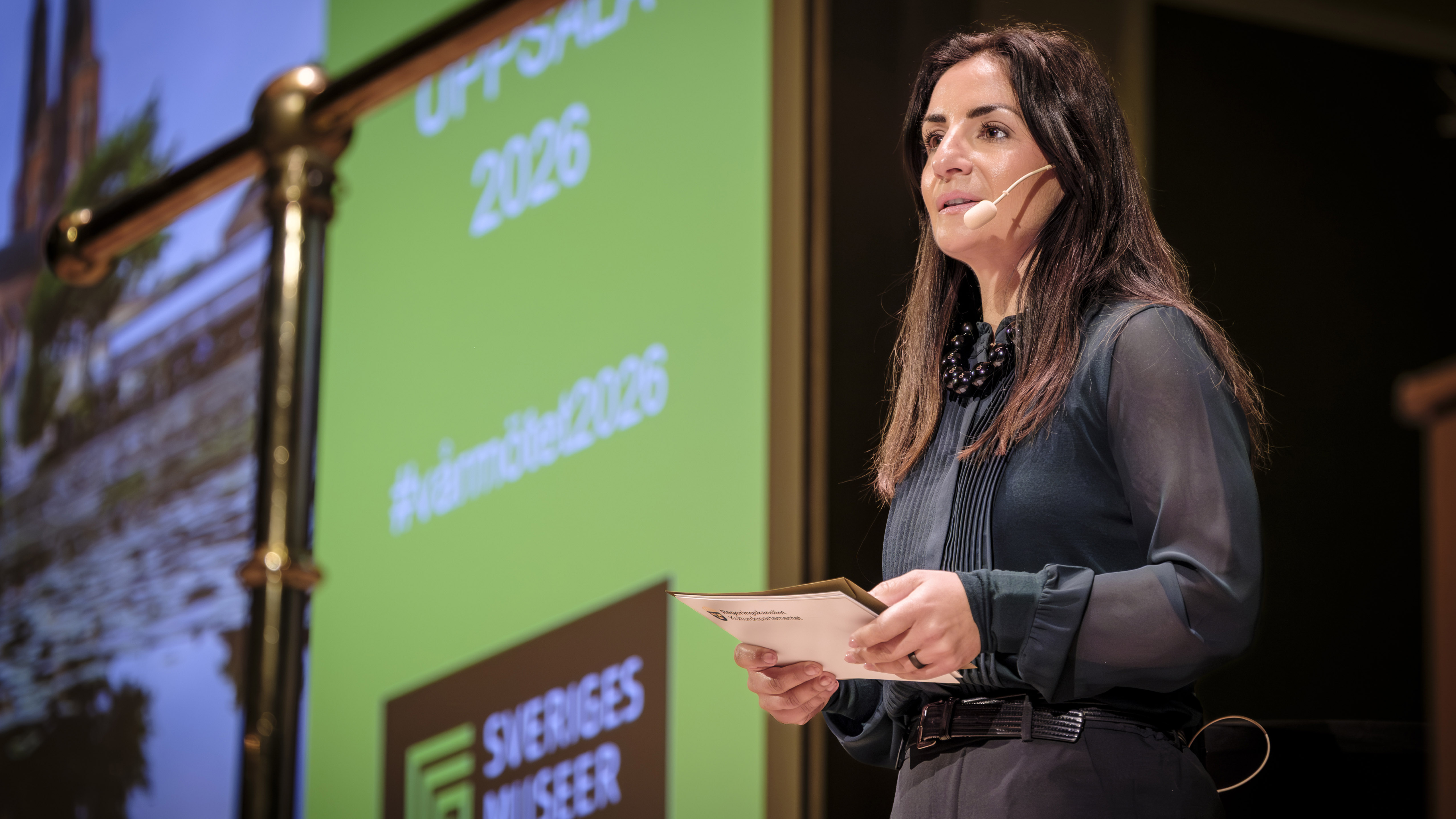 Kulturminister Parisa Liljestrand på scen med en skärm som visar texten Sveriges museer bakom. 