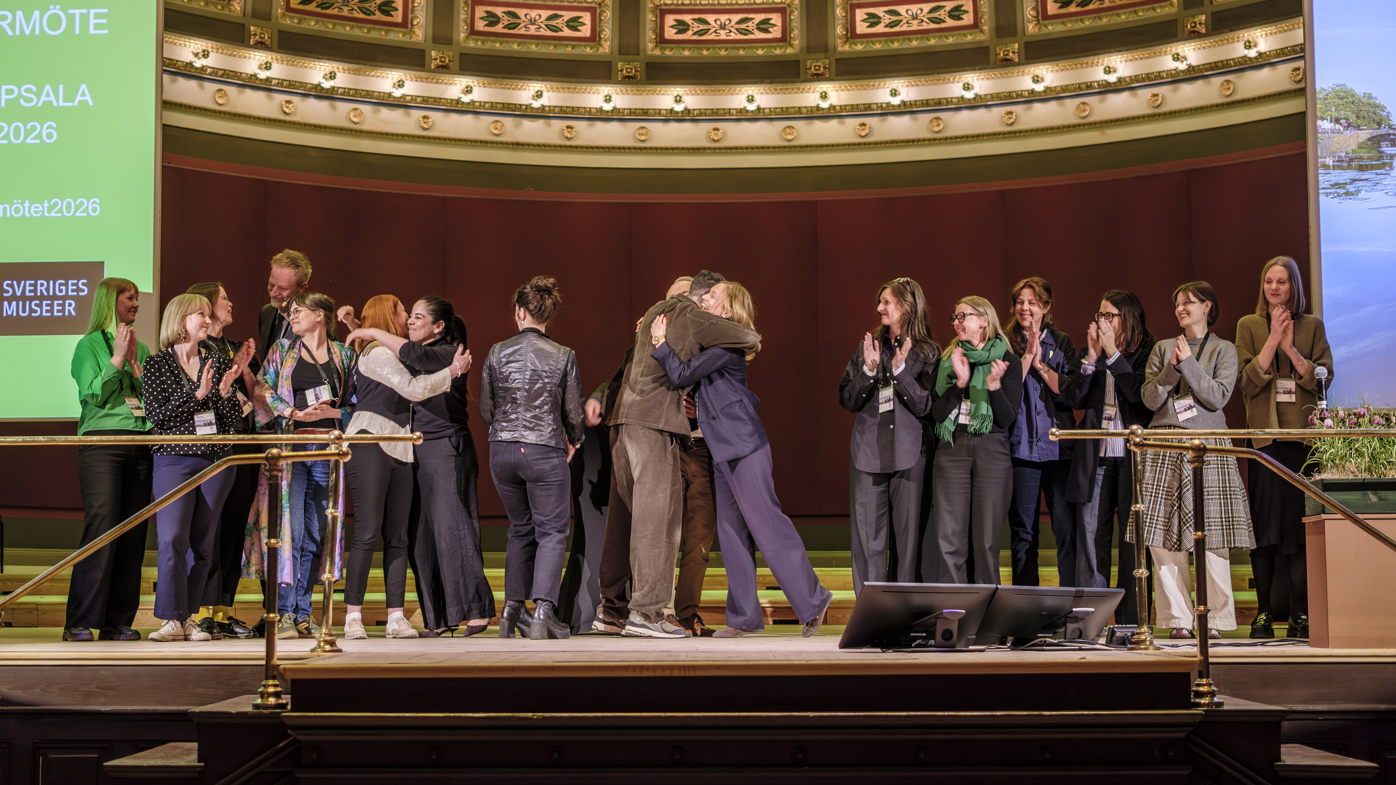 Glada personer kramar om varandra på scen på Sveriges museers årsmöte.