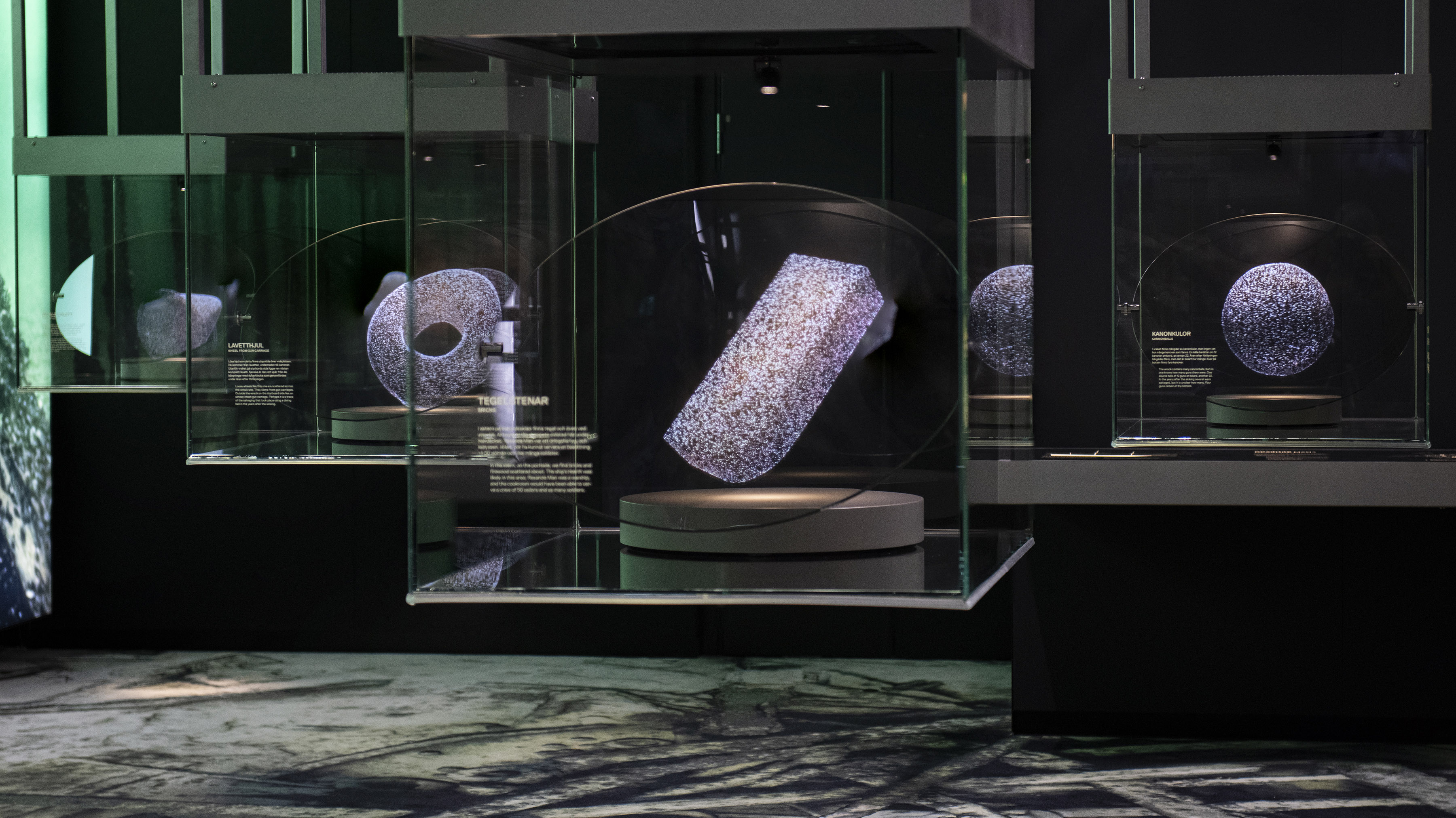 The exhibition Resande man at Vrak with photos and carpet with photos of the wreck, display cases with holograms of findings from the ship.