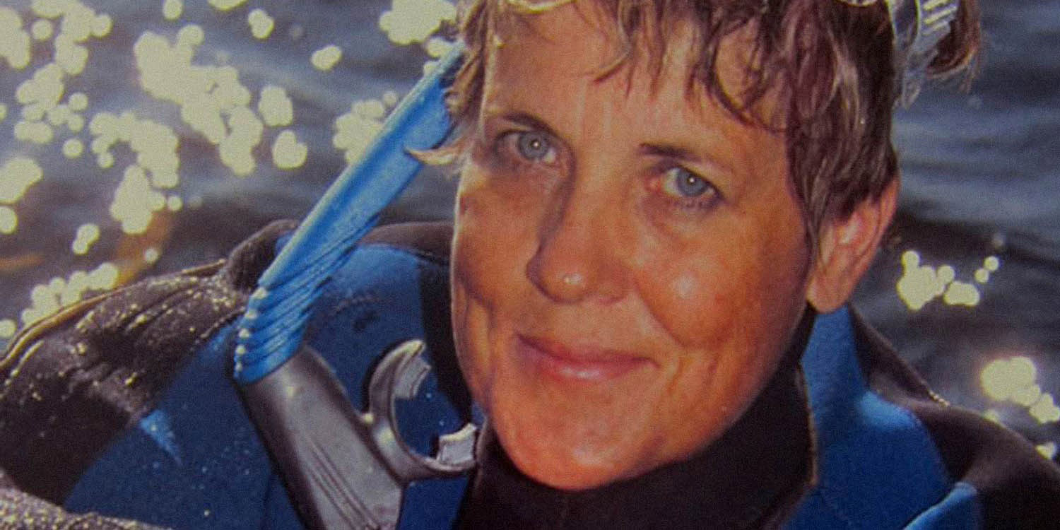 Bild av Catharina Ingelman-Sundberg i dykardräkt med ruffisgt hår framför vattenyta.