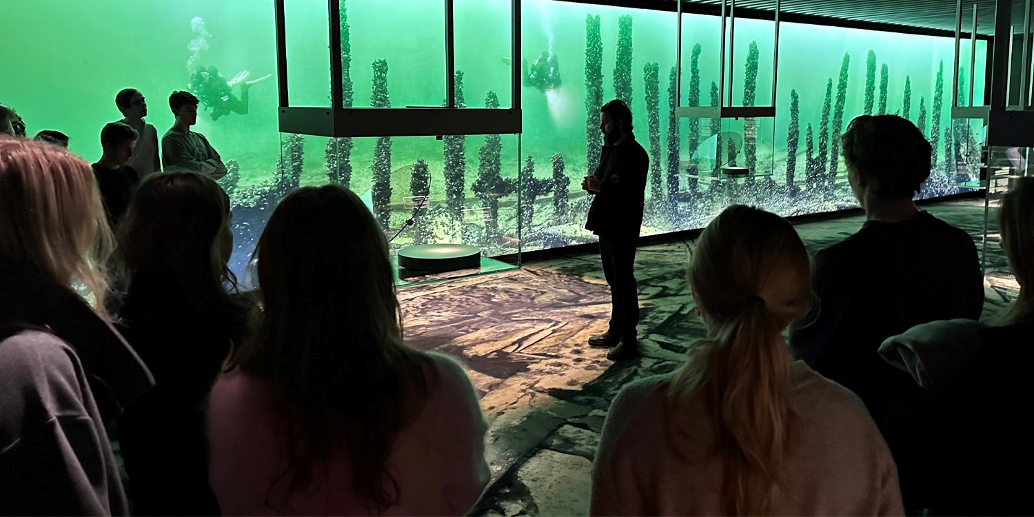 Vraks pedagog håller en skolvisning i utställningen Resande Man